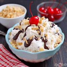 a bowl filled with ice cream and cherries on top of a table next to bowls of cereal