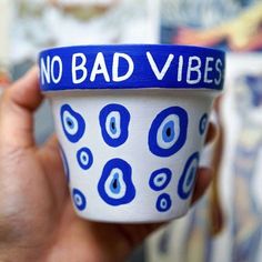 a hand holding a cup with the words no bad vibes painted on it in blue and white