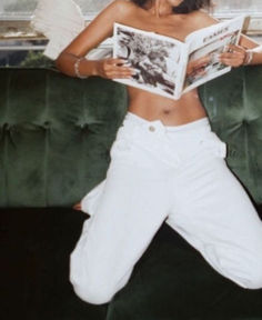 a woman in white pants is reading a magazine