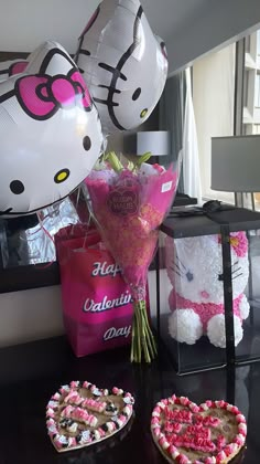 hello kitty balloons and heart shaped cakes on a table