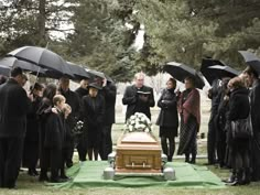 a group of people with umbrellas standing around a grave