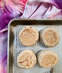 three biscuits sitting on top of a metal pan next to a pink and purple towel