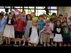 a group of children standing in front of a stained glass window with their hands together