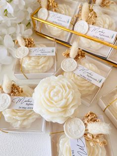 wedding favors in clear boxes with white flowers and gold trimmings on the sides