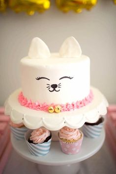 a cat cake and cupcakes on a table