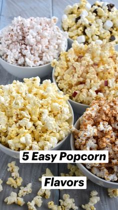 four bowls filled with popcorn sitting on top of a wooden table