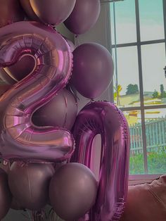 the number two is made out of purple and silver balloons in front of a window