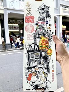 a person holding up a drawing on the side of a road with buildings in the background