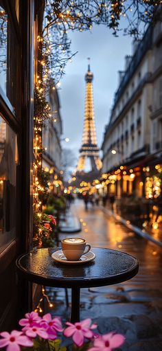 a coffee cup on a table in front of the eiffel tower at night