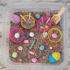 a plastic container filled with lots of different types of candies and cupcakes