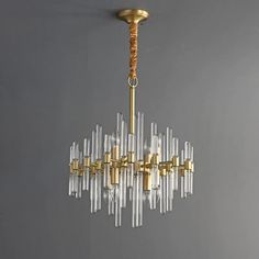 a chandelier hanging from the ceiling with clear glass rods and gold fittings