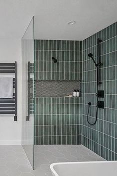 a bathroom with green tiled walls and flooring, along with a white bathtub