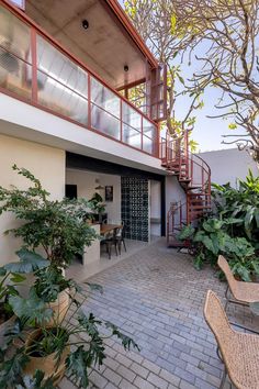 a patio with chairs and tables next to a staircase that leads up to the second floor