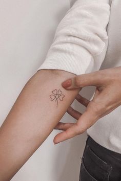 a woman's arm with a small four leaf clover tattoo on it