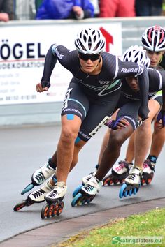 three men riding roller blades down a street