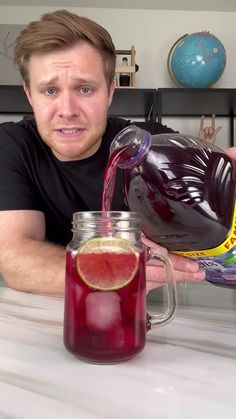 a man is pouring some liquid into a glass jar with a slice of fruit in it