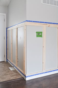 an unfinished room with white walls and blue tape on the wall next to the door