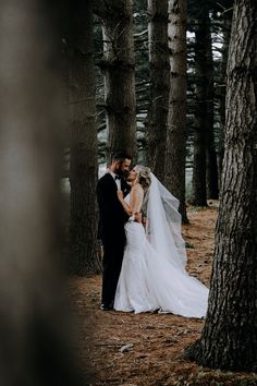 a bride and groom kissing in the woods