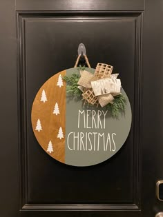 a christmas ornament hanging on a door in front of a wooden sign that says merry christmas