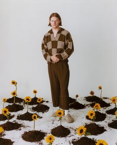 a man standing in front of a pile of dirt with sunflowers growing out of it