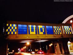 an overpass at night with cars driving under it and brightly colored windows on the side