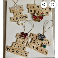 scrabble tiles with words and bows hanging from them on a white board that says let it snow, joy, peace, to the earth, and world