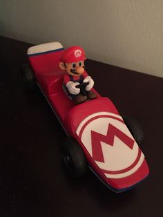 a nintendo mario kart toy sitting on top of a wooden table next to a wall