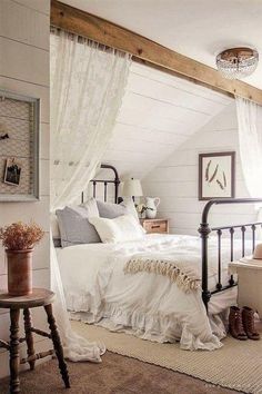 a bedroom with white walls and wooden flooring has a metal bed frame that is topped with pillows and blankets