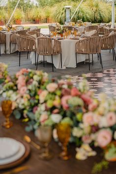 an outdoor dining area with tables, chairs and flowers on the tablecloths in front of them