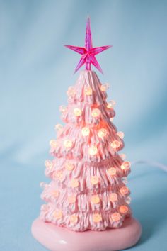 a small pink christmas tree with lights on it's base and a star on top