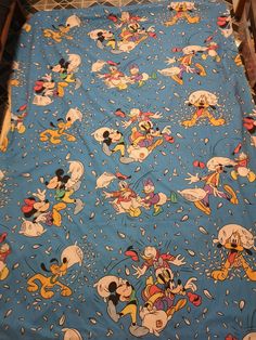 a mickey mouse bed spread with many different cartoon characters on blue sheets and white polka dots