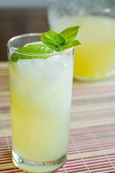 a close up of a glass on a table with a drink in it and mint garnish