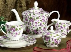 a tea set with purple and green flowers on it