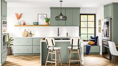 a kitchen with green cabinets and white stools in front of an island countertop