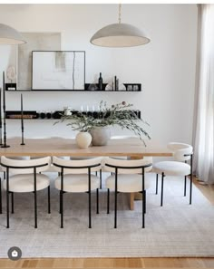 a dining room table surrounded by white chairs