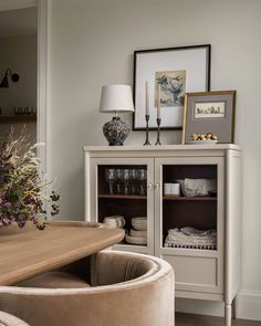 a white cabinet sitting next to a wooden table in a living room filled with furniture