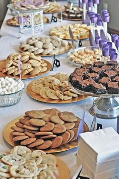 a table topped with lots of different types of cookies and pies on plates next to each other