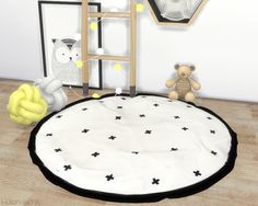 a teddy bear is sitting on the floor next to a round rug with black and white stars