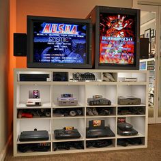 two televisions sitting on top of a white shelf next to each other in a room