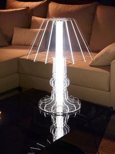 a glass table lamp sitting on top of a black table next to a couch in a living room