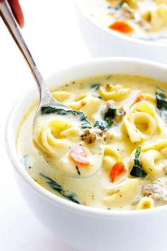 a white bowl filled with pasta and spinach soup