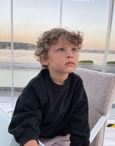 a little boy sitting in a chair looking up