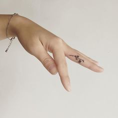 a person's hand with a small tattoo on it and a chain around the wrist