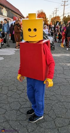 a child dressed as a lego character with a red box on his head and blue pants