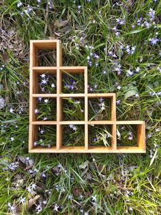 an arrangement of wooden squares in the grass with flowers growing out of one side and another on the other