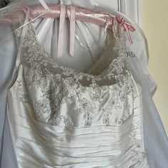 a dress hanging on a rack in front of a white door with pink ribbon and bows