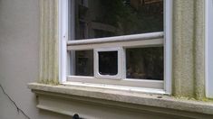 a cat sitting in the window sill of a house next to an open window