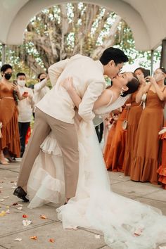 a bride and groom kissing in front of a group of wedding guests at the end of their ceremony