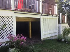 an open garage door on the side of a house with flowers growing in the yard