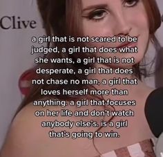 a woman talking into a microphone next to a sign with the caption girl that is not scared to be judged, a girl that does what she wants, a girl that is not desperate